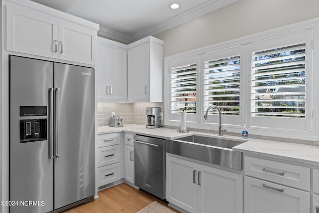 kitchen with stainless steel appliances, sink, light hardwood / wood-style floors, crown molding, and white cabinetry