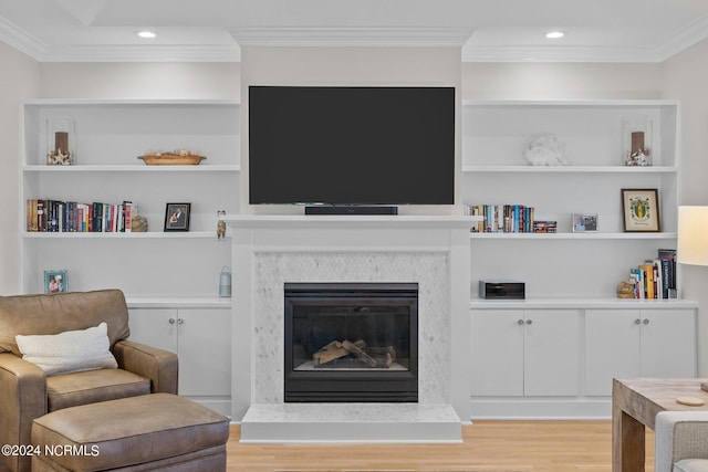 living room with built in shelves, a premium fireplace, and light wood-type flooring