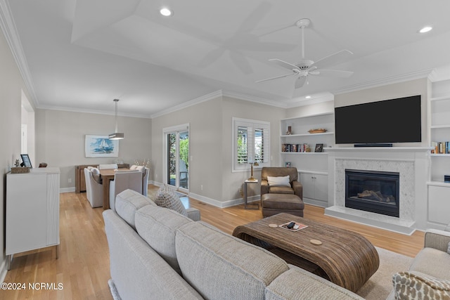 living room with ceiling fan, light hardwood / wood-style flooring, a premium fireplace, and crown molding