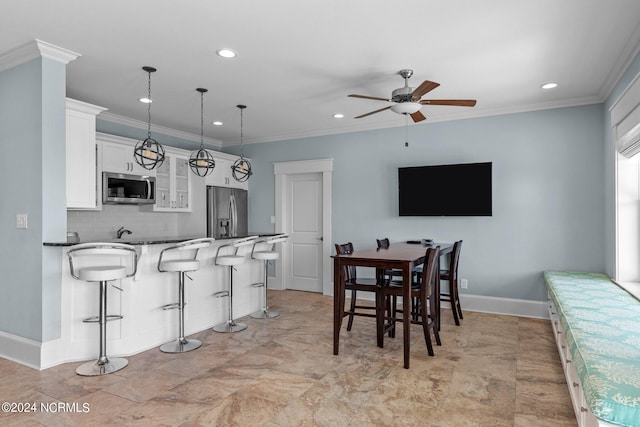 kitchen with decorative light fixtures, white cabinetry, stainless steel appliances, a kitchen bar, and decorative backsplash