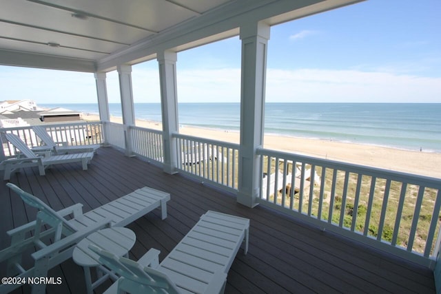 wooden terrace featuring a beach view and a water view