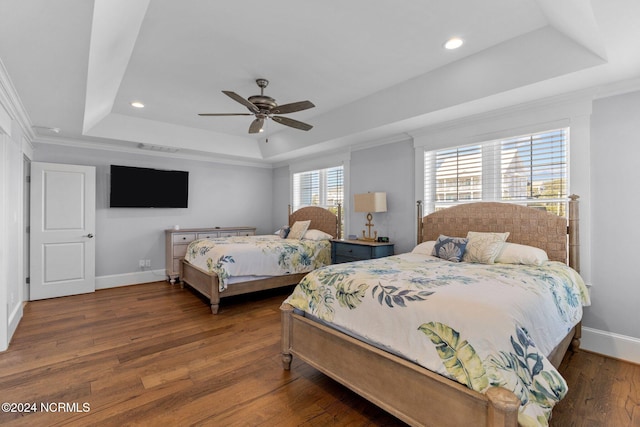 bedroom with ceiling fan, a raised ceiling, dark hardwood / wood-style floors, and ornamental molding