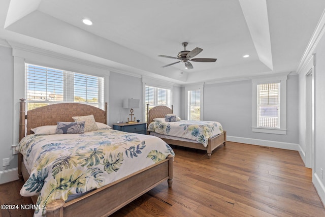 bedroom with hardwood / wood-style flooring, crown molding, ceiling fan, and a raised ceiling