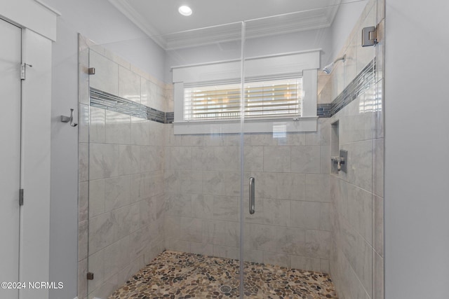 bathroom with a shower with shower door and ornamental molding