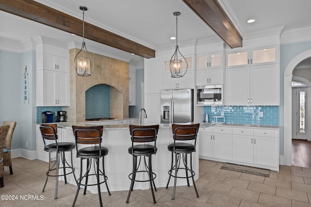 kitchen featuring white cabinets, an island with sink, pendant lighting, beam ceiling, and stainless steel appliances