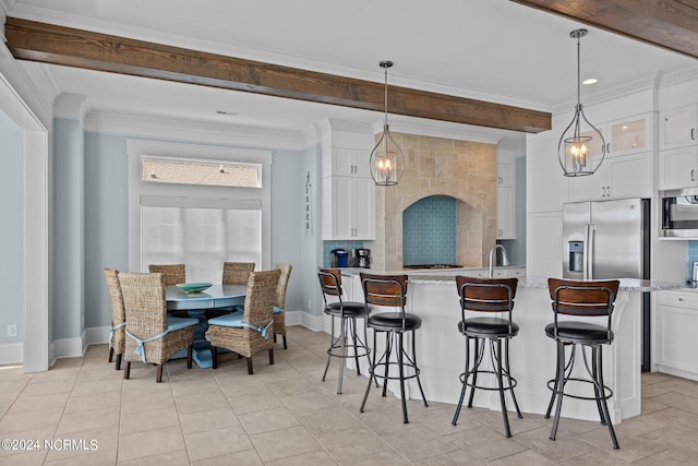 kitchen featuring light stone counters, stainless steel appliances, hanging light fixtures, and white cabinetry