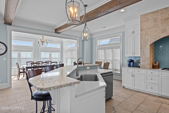 kitchen with pendant lighting, an island with sink, sink, and white cabinetry