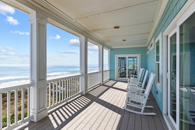 wooden terrace featuring a beach view and a water view