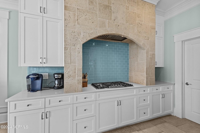 kitchen featuring ornamental molding, stainless steel gas cooktop, decorative backsplash, and white cabinetry