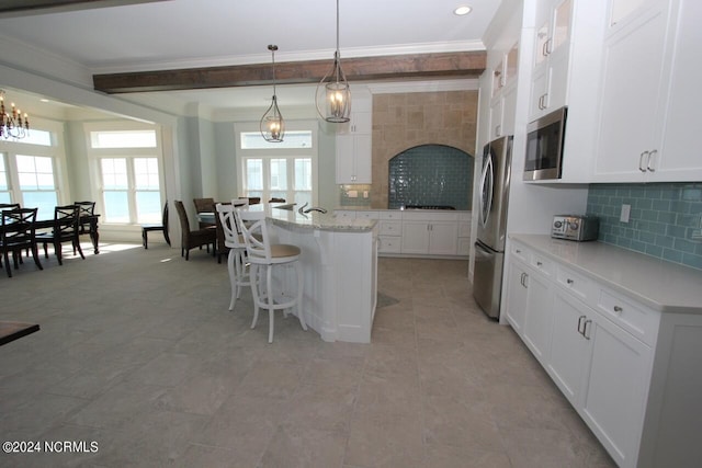 kitchen featuring stainless steel appliances, white cabinetry, a breakfast bar area, a center island with sink, and decorative light fixtures