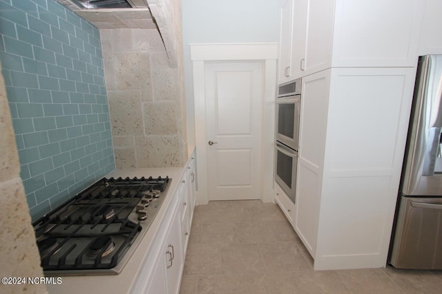 kitchen featuring stainless steel appliances, light tile patterned flooring, white cabinets, and light stone counters