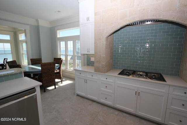 kitchen with appliances with stainless steel finishes, crown molding, backsplash, and white cabinets