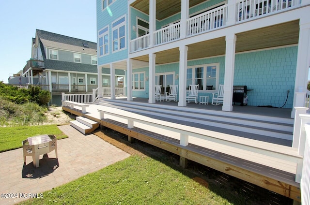 exterior space with a yard, a wooden deck, a patio area, and a balcony