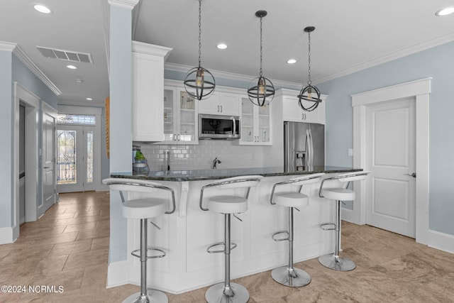 kitchen featuring stainless steel appliances, a kitchen breakfast bar, decorative light fixtures, and white cabinetry