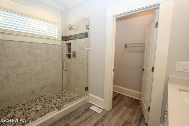 bathroom with wood-type flooring, vanity, crown molding, and an enclosed shower