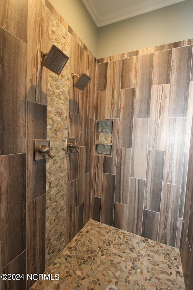 bathroom featuring ornamental molding and tiled shower