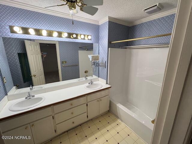 bathroom with vanity, washtub / shower combination, ornamental molding, and a textured ceiling