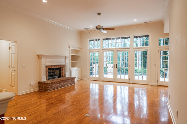 unfurnished living room with a fireplace, french doors, light hardwood / wood-style flooring, and crown molding