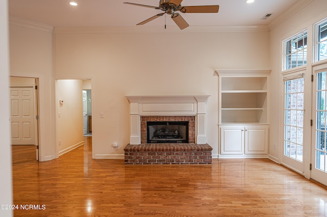 unfurnished living room with light hardwood / wood-style floors, a brick fireplace, ceiling fan, and crown molding