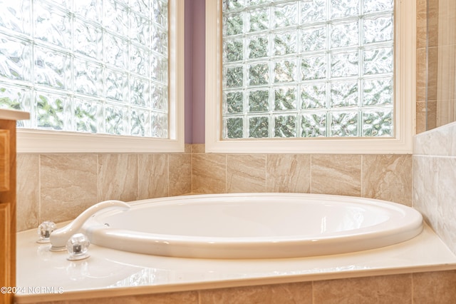 bathroom with tiled tub and a wealth of natural light