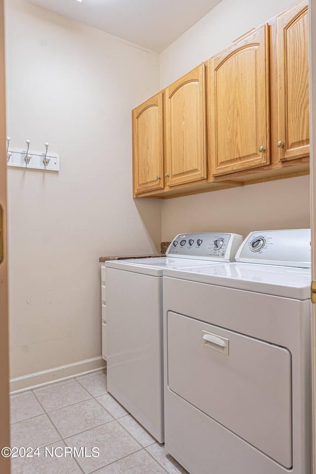 laundry room featuring cabinets, light tile patterned floors, and washer and dryer