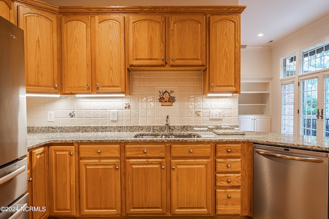 kitchen with light stone countertops, decorative backsplash, stainless steel appliances, crown molding, and sink