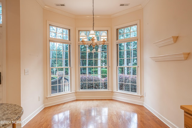 unfurnished dining area featuring hardwood / wood-style flooring, an inviting chandelier, and ornamental molding