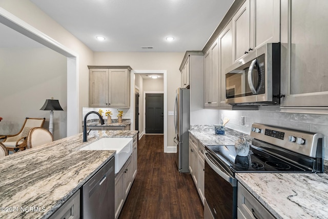 kitchen with light stone countertops, dark wood-style floors, appliances with stainless steel finishes, and a sink