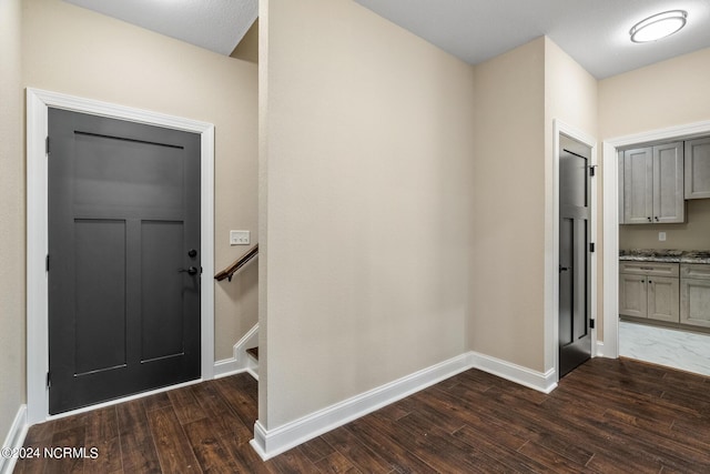 foyer entrance with dark wood-style floors and baseboards