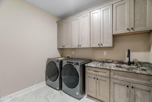 laundry room with a sink, baseboards, marble finish floor, cabinet space, and washer and clothes dryer