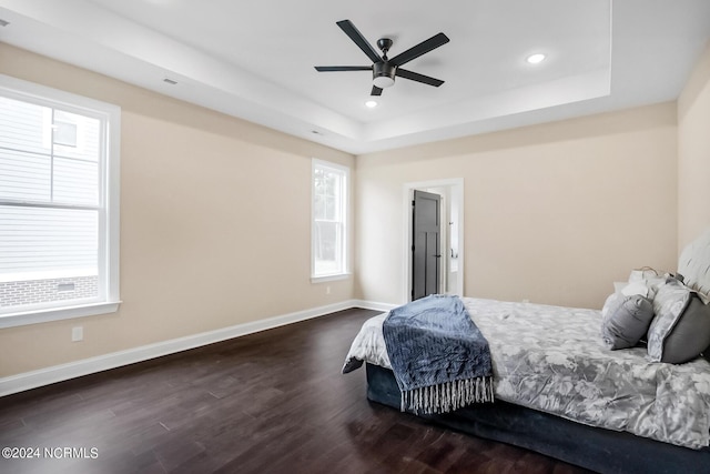 bedroom featuring recessed lighting, a raised ceiling, baseboards, and wood finished floors