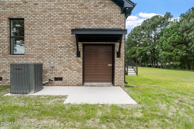 view of exterior entry with crawl space, brick siding, a lawn, and cooling unit