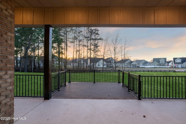 patio terrace at dusk with a lawn and a residential view