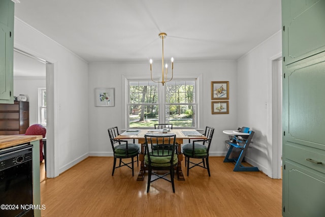 dining room with ornamental molding, a chandelier, and light hardwood / wood-style floors