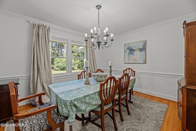 dining room with an inviting chandelier, crown molding, and light hardwood / wood-style flooring