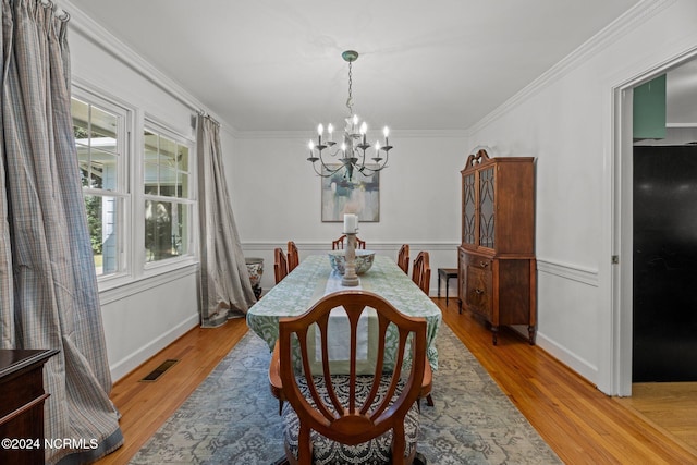 dining space with ornamental molding, a notable chandelier, and light hardwood / wood-style floors