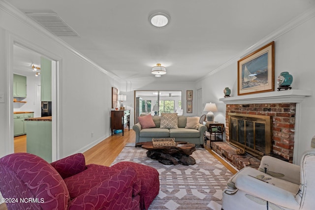 living room featuring ornamental molding, a fireplace, and light hardwood / wood-style floors