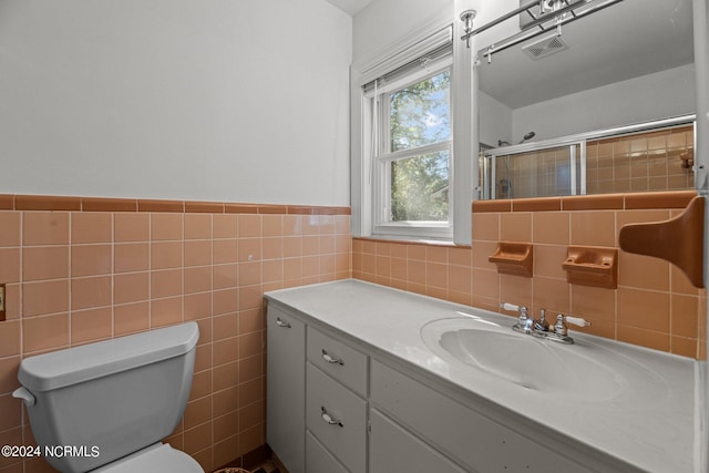 bathroom with vanity, walk in shower, toilet, and tile walls