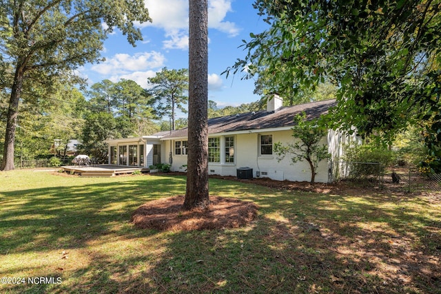 back of property with a yard, a deck, and central AC unit