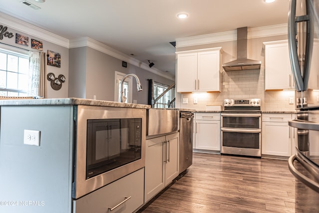 kitchen with white cabinets, appliances with stainless steel finishes, dark hardwood / wood-style flooring, and wall chimney range hood