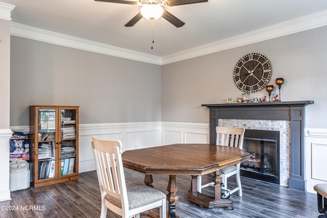 dining space featuring ceiling fan, a tile fireplace, dark hardwood / wood-style floors, and crown molding