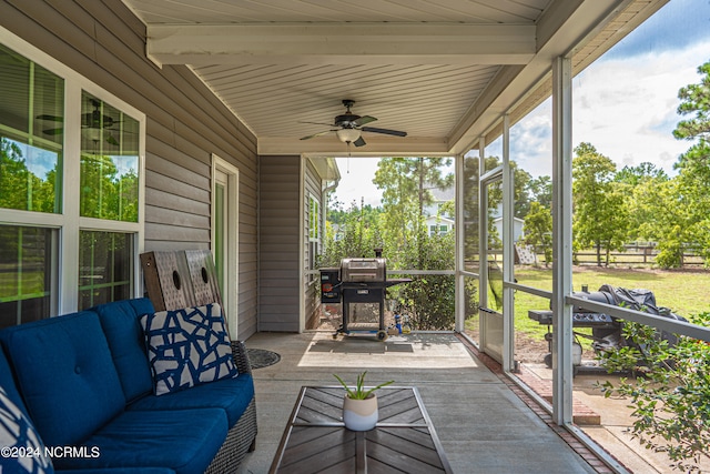 sunroom / solarium featuring ceiling fan and beam ceiling