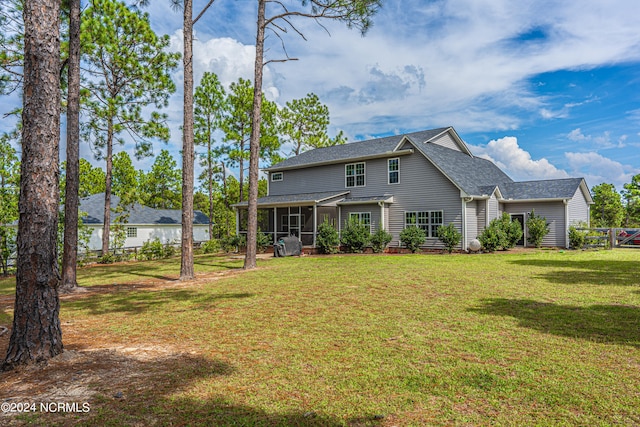 back of property featuring a sunroom and a lawn