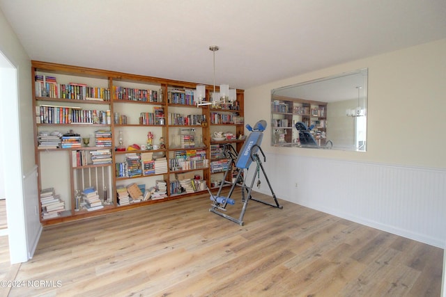 game room featuring wooden walls, a chandelier, and hardwood / wood-style floors