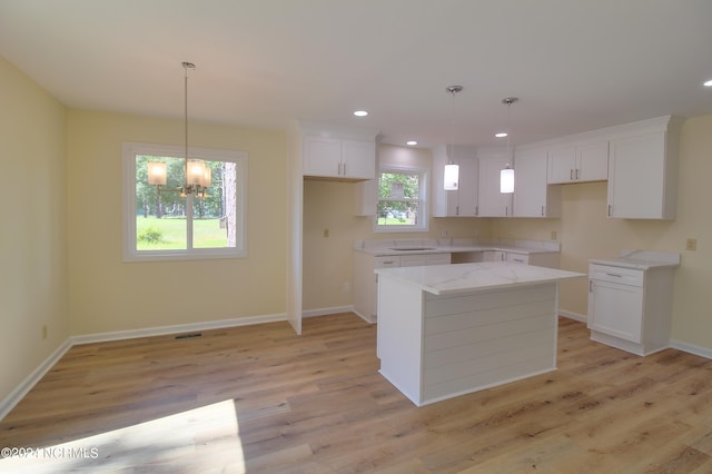 kitchen featuring white cabinets, light hardwood / wood-style flooring, pendant lighting, and a kitchen island