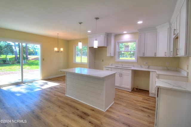 kitchen featuring decorative light fixtures, a kitchen island, light hardwood / wood-style flooring, and white cabinets