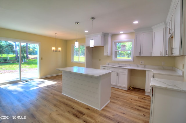 kitchen featuring a kitchen island, light wood-type flooring, plenty of natural light, and white cabinetry