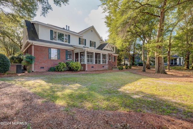 rear view of property with a sunroom and a lawn