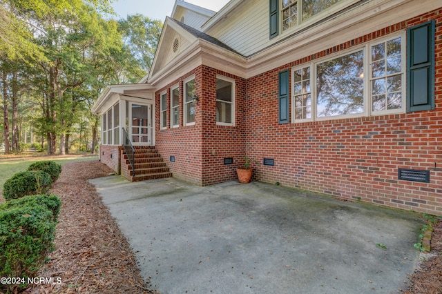 view of property exterior featuring a sunroom and a patio