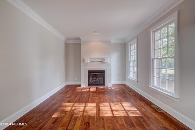 unfurnished living room with wood-type flooring, plenty of natural light, and ornamental molding